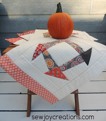 Liberated Churn Dash placemats posing with a pumpkin
